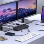 Biurko z laptopem podłączonym do dodatkowych monitorów i sieci przez stację dokującą USB-C.